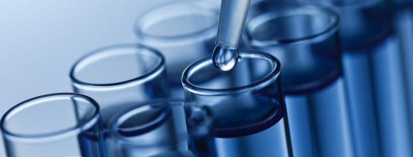 A close-up image of a liquid being added to a test tube with a dropper