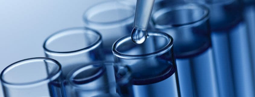 A close-up image of a liquid being added to a test tube with a dropper